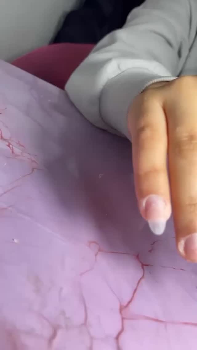 Pearl-white gel nails held over a glitter palette at Rullier Beauty & Spa